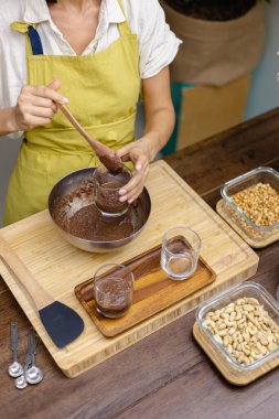 Kadın mutfakta chia pudingi hazırlıyor, alt tabakayı hazırlıyor.