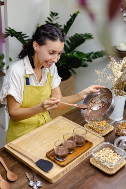 Kadın mutfakta chia pudingi hazırlıyor, alt tabakayı hazırlıyor.