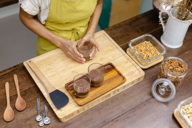 Kadın mutfakta chia pudingi hazırlıyor, alt tabakayı hazırlıyor.
