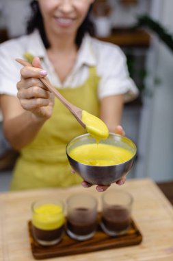 Mutfaktaki kadın mangolu puding yapıyor.