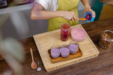 Çilekli, yaban mersinli ve bademli chia pudingleri yapan kadın.
