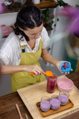Çilekli, yaban mersinli ve bademli chia pudingleri yapan kadın.