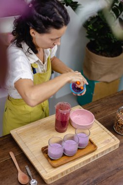 Çilekli, yaban mersinli ve bademli chia pudingleri yapan kadın.