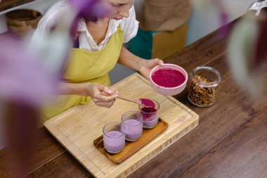 Çilekli, yaban mersinli ve bademli chia pudingleri yapan kadın.