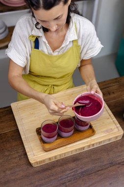 Çilekli, yaban mersinli ve bademli chia pudingleri yapan kadın.