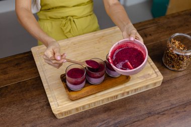 Çilekli, yaban mersinli ve bademli chia pudingleri yapan kadın.