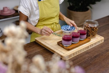 Çilekli, yaban mersinli ve bademli chia pudingleri yapan kadın.