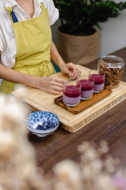 Çilekli, yaban mersinli ve bademli chia pudingleri yapan kadın.