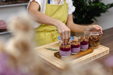 Çilekli, yaban mersinli ve bademli chia pudingleri yapan kadın.