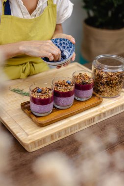 Çilekli, yaban mersinli ve bademli chia pudingleri yapan kadın.