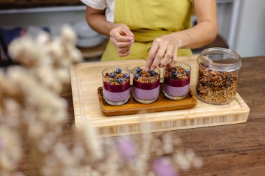 Çilekli, yaban mersinli ve bademli chia pudingleri yapan kadın.