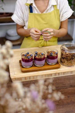 Çilekli, yaban mersinli ve bademli chia pudingleri yapan kadın.