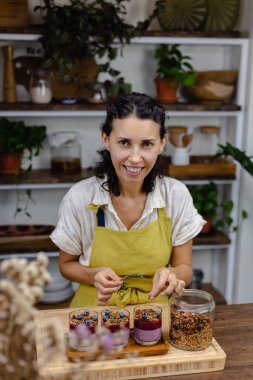 Çilekli, yaban mersinli ve bademli chia pudingleri yapan kadın.