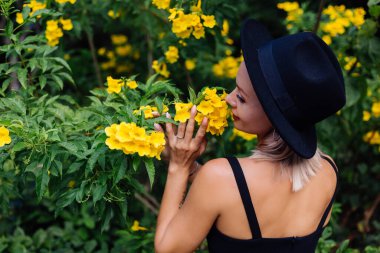 Parktaki mutlu kadın sarı Tayland çiçekleriyle çevrili.