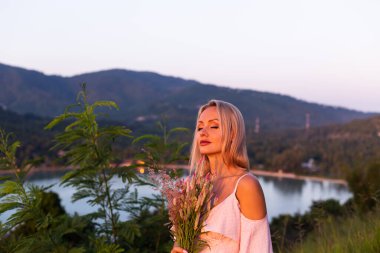 Romantik portre, sakin, güzel bir kadının tropikal parktaki vahşi pembe çiçekleri.