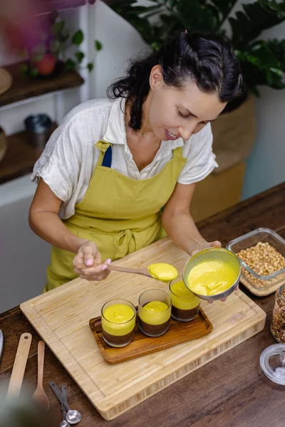 Mutfaktaki kadın mangolu puding yapıyor.