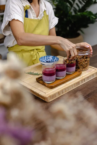Çilekli, yaban mersinli ve bademli chia pudingleri yapan kadın.