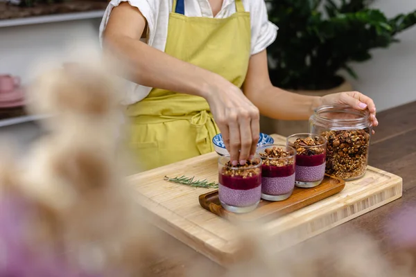 Çilekli, yaban mersinli ve bademli chia pudingleri yapan kadın.