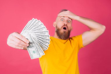 Pembe arka plandaki Avrupalı adam 100 dolarlık fanı ile şok oldu. Alnına dokunuyor ve ağzı açık kalıyor.