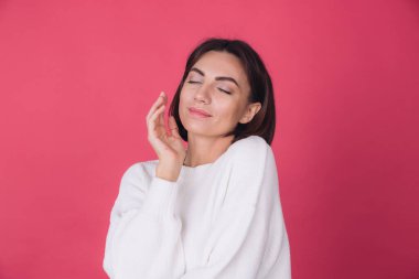 Pembe arka planda beyaz süveter giyen güzel bir kadın. Aşk kavramı. El ele tutuşup kendini kopyalanmış fotokopi odası kapalı gözlerle kucaklıyor.