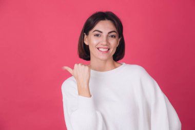 Pembe arka planda beyaz süveter giyen güzel bir kadın parmak izole edilmiş fotokopi aletiyle gülümseme noktası bırakmış.