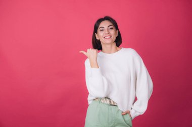 Pembe arka planda beyaz süveter giyen güzel bir kadın parmak izole edilmiş fotokopi aletiyle gülümseme noktası bırakmış.