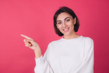 Pembe arka planda beyaz süveter giyen güzel bir kadın işaret parmağı izole edilmiş fotokopi aletiyle gülümseme noktası bırakmış.