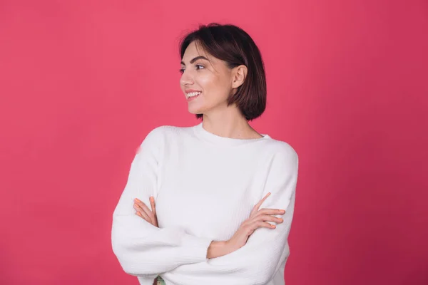 stock image Beautiful woman in casual white sweater on pink red background with crossed hands smile look to left isolated copy space