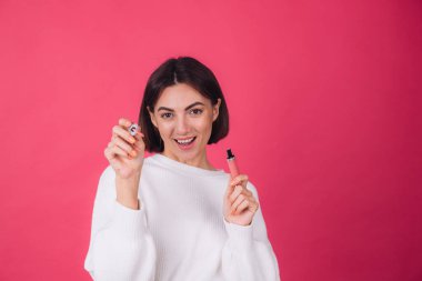 Pembe arka planda, beyaz süveter giyen şık bir kadın. İzole edilmiş, mutlu, pozitif ruj sürmüş.