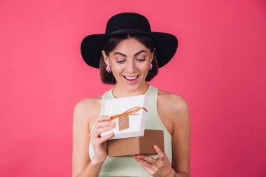 Pembe arka planda şapkalı şık bir kadın tecrit edilmiş, açık bir hediye kutusu ve şaşkın bir yüzü var.