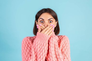 Mavi arka planda izole edilmiş, koyu pembe kazaklı genç esmer. Fotokopi alanı.