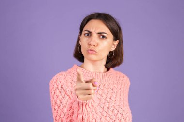 Mor arka planda izole edilmiş genç esmer, öfkeyle bağırıyor, seni kınıyor, doğrudan kameraya işaret ediyor, seni suçluyor.