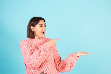 Pembe süveterli genç esmer, mavi arka planda soyutlanmış.