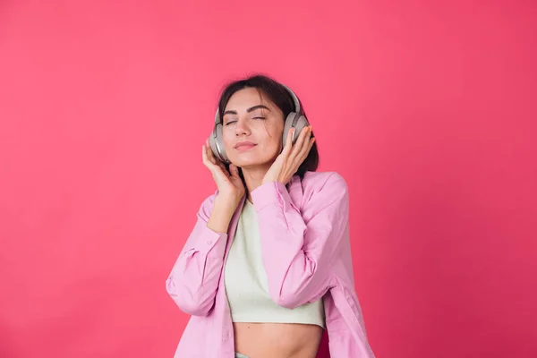 幸せな正の女性でヘッドフォン上のピンク赤の背景正のダンス移動楽しい音 — ストック写真