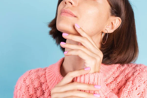 美しいコンセプト 暖かいセーターと青い壁 春の気分を背景に明るいピンクの爪の色のマニキュアを持つ美しい女性 — ストック写真