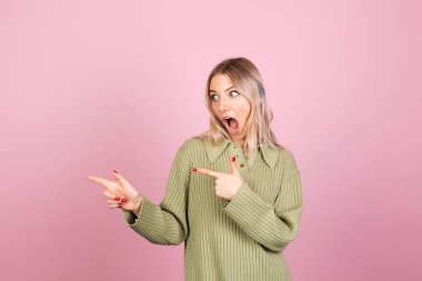 Pembe arka planda sıradan örülü süveter giyen güzel Avrupalı kadın işaret parmağıyla bırakılan heyecanlı noktayı şaşırttı.
