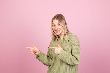 Pembe arka planda sıradan örülü süveter giyen güzel Avrupalı kadın işaret parmağıyla bırakılan heyecanlı noktayı şaşırttı.