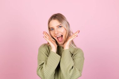 Pembe arka planda gündelik süveter giyen güzel Avrupalı kadın. Kameraya mutlu bir bakış.