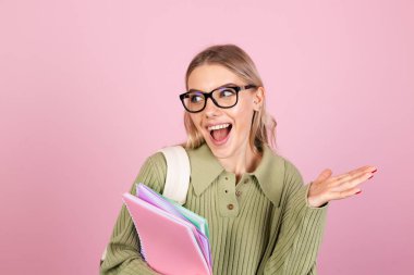 Pembe arka planda gündelik süveter giyen güzel Avrupalı bir kadın. Notları var. Heyecan dolu duygular açık, eğitim kavramı açık.