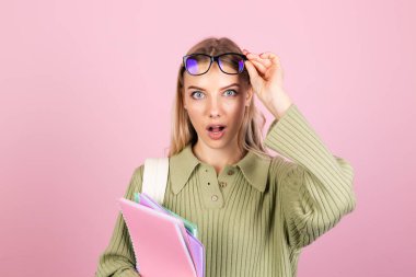 Pembe arka planda gündelik süveter giyen güzel Avrupalı kadın. Ağzını açık tutmak şok edici, eğitim kavramı.