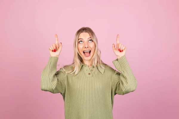 かわいいですヨーロッパの女性でカジュアルなニットセーターオンピンクの背景幸せな驚きポイントアップとともにインデックス指コピースペース — ストック写真