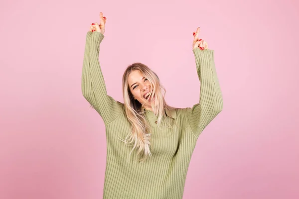 ピンクの背景にカジュアルなセーターのかなりヨーロッパの女性は特別な瞬間を待ちます 指を渡り続けます 願いのジェスチャーを作ります — ストック写真
