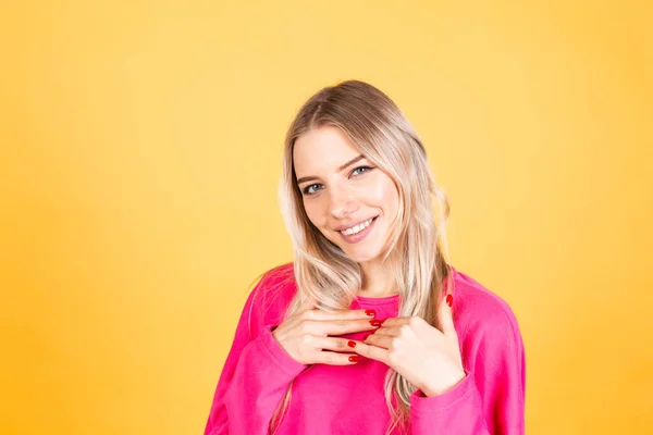 かなりヨーロッパの女性でピンクブラウスに黄色の背景正の感情笑顔幸せな陽気な手上の胸 — ストック写真