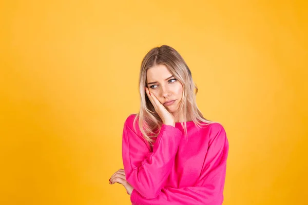 かなりヨーロッパの女性でピンクブラウスで黄色の背景見て疲れていると退屈でうつ病の問題 — ストック写真