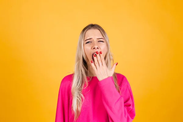 かなりヨーロッパの女性でピンクブラウスで黄色の背景退屈Yawning疲れてカバー口とともに手 — ストック写真