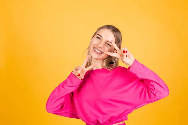 Sarı Arka Planda Pembe Bluzlu Güzel Avrupalı Kadın Zafer Jesti — Stok fotoğraf