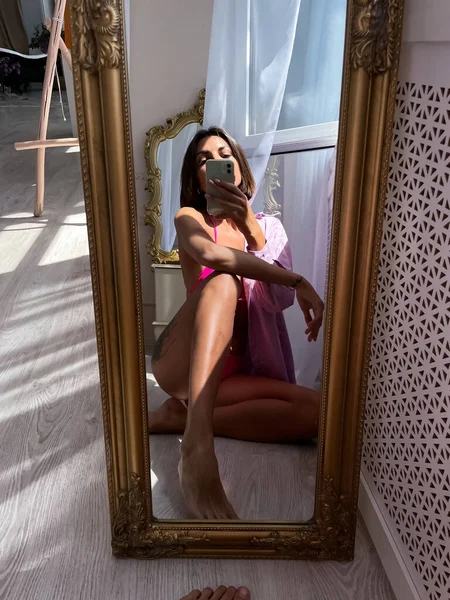 完璧な体で日焼けした女性をフィット ビキニでヒップの入れ墨 ソーシャルメディアのために自宅でミラーで携帯電話で写真自撮り 夏のコンセプト — ストック写真