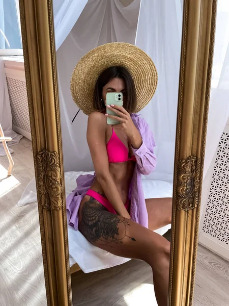 适合拥有完美身材 髋部纹身的晒黑的女人穿比基尼 在家里的镜子里为社交媒体 夏季的概念拍照 — 图库照片