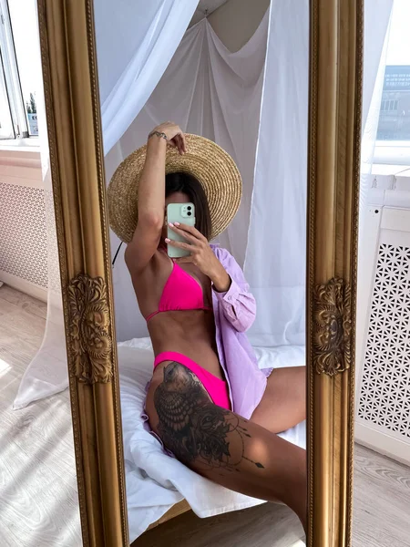 适合拥有完美身材 髋部纹身的晒黑的女人穿比基尼 在家里的镜子里为社交媒体 夏季的概念拍照 — 图库照片
