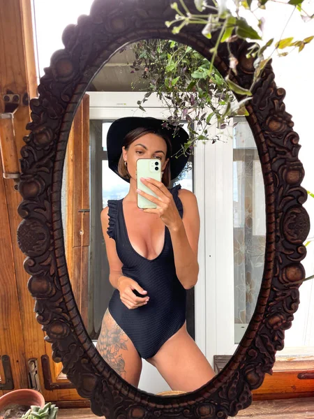 在家里 漂亮的女人穿着黑色夏装 腿上有个很大的纹身 适合晒晒黑衣服 在社交媒体上的故事和贴文都是在手机上拍照的 — 图库照片